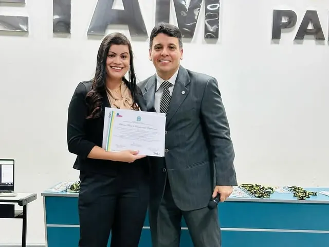 Any Ribeiro recebendo certificado em evento de formação, ao lado de um instrutor