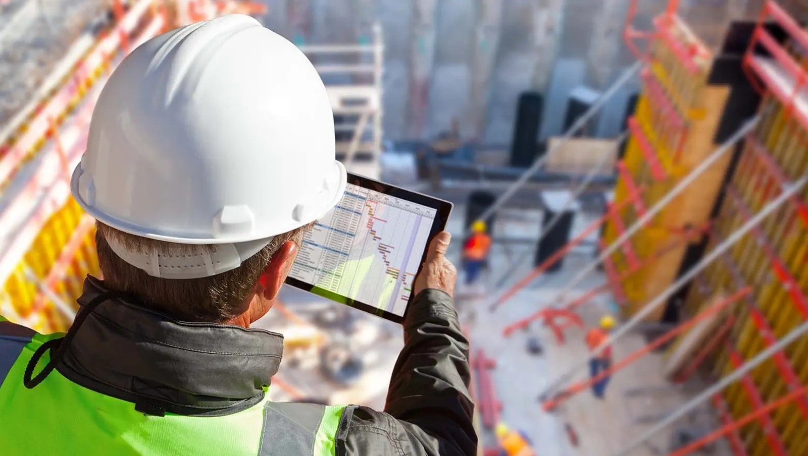 Engenheira acompanhando cronograma da obra pelo tablet, vista aérea do canteiro