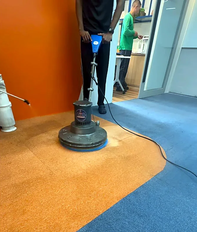 Funcionário passando a máquina de limpeza no carpete de um escritório